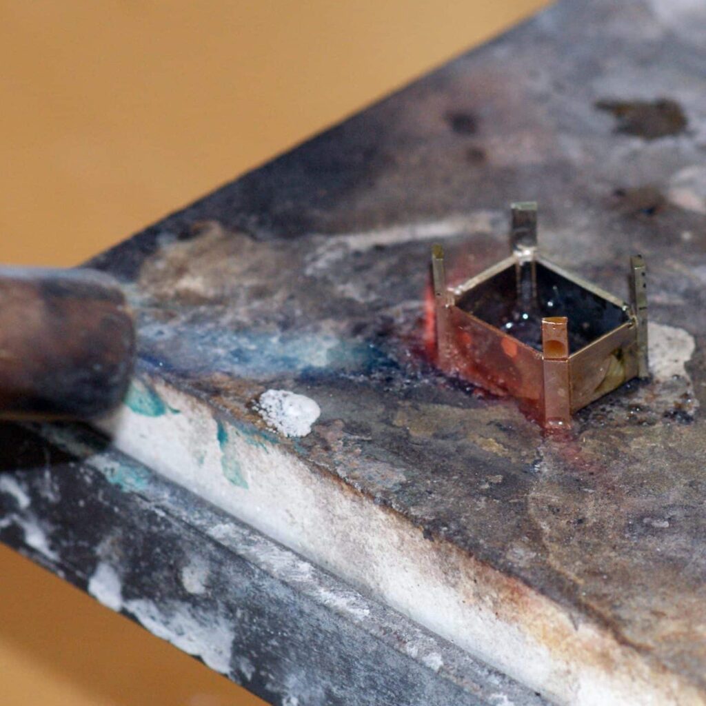 A prong being soldered on the soldering block with a torch and flux